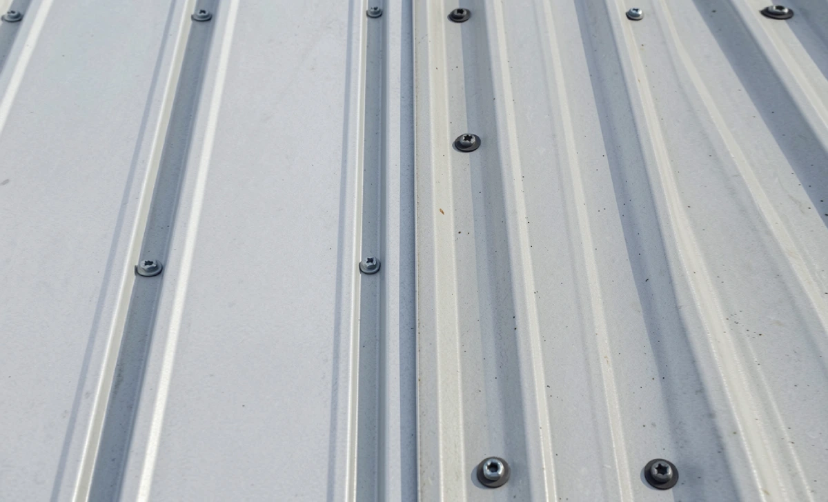 Side by side comparison of standing seam and exposed fastener metal roof panels